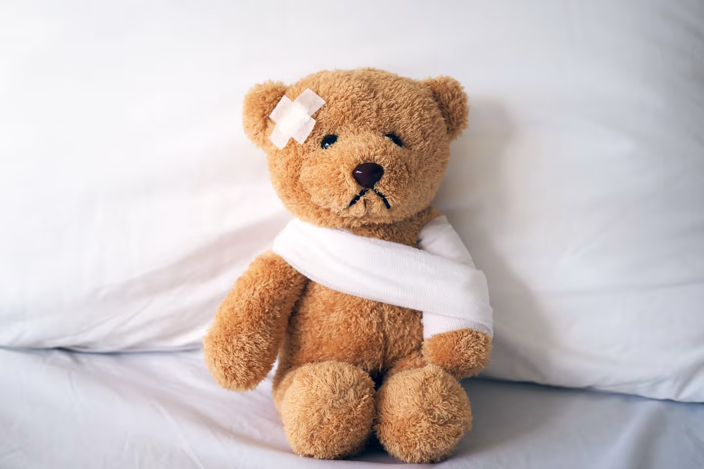 a teddy bear with a bandaid and arm bandage